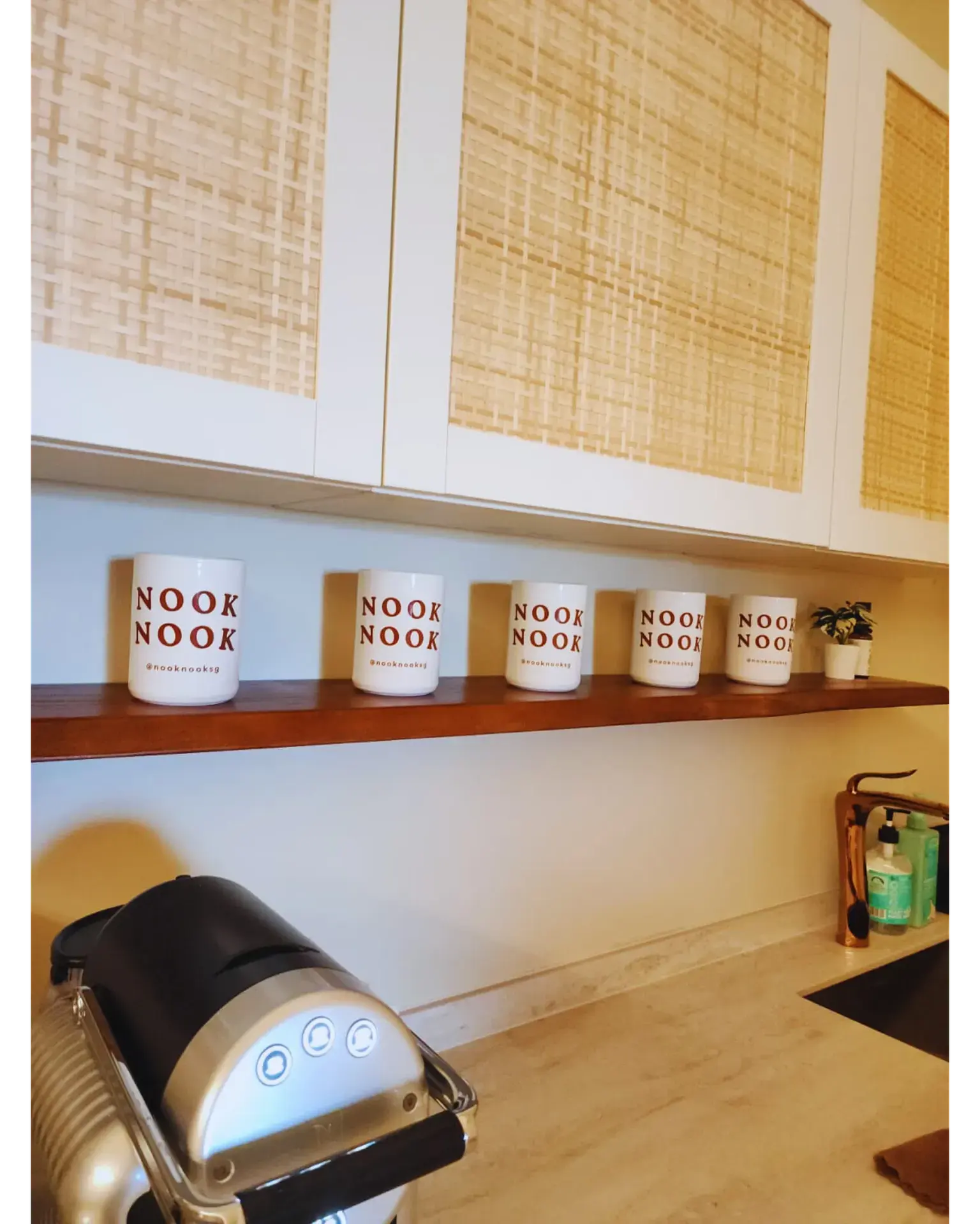 The shelf of Nook Nook mugs above the counter