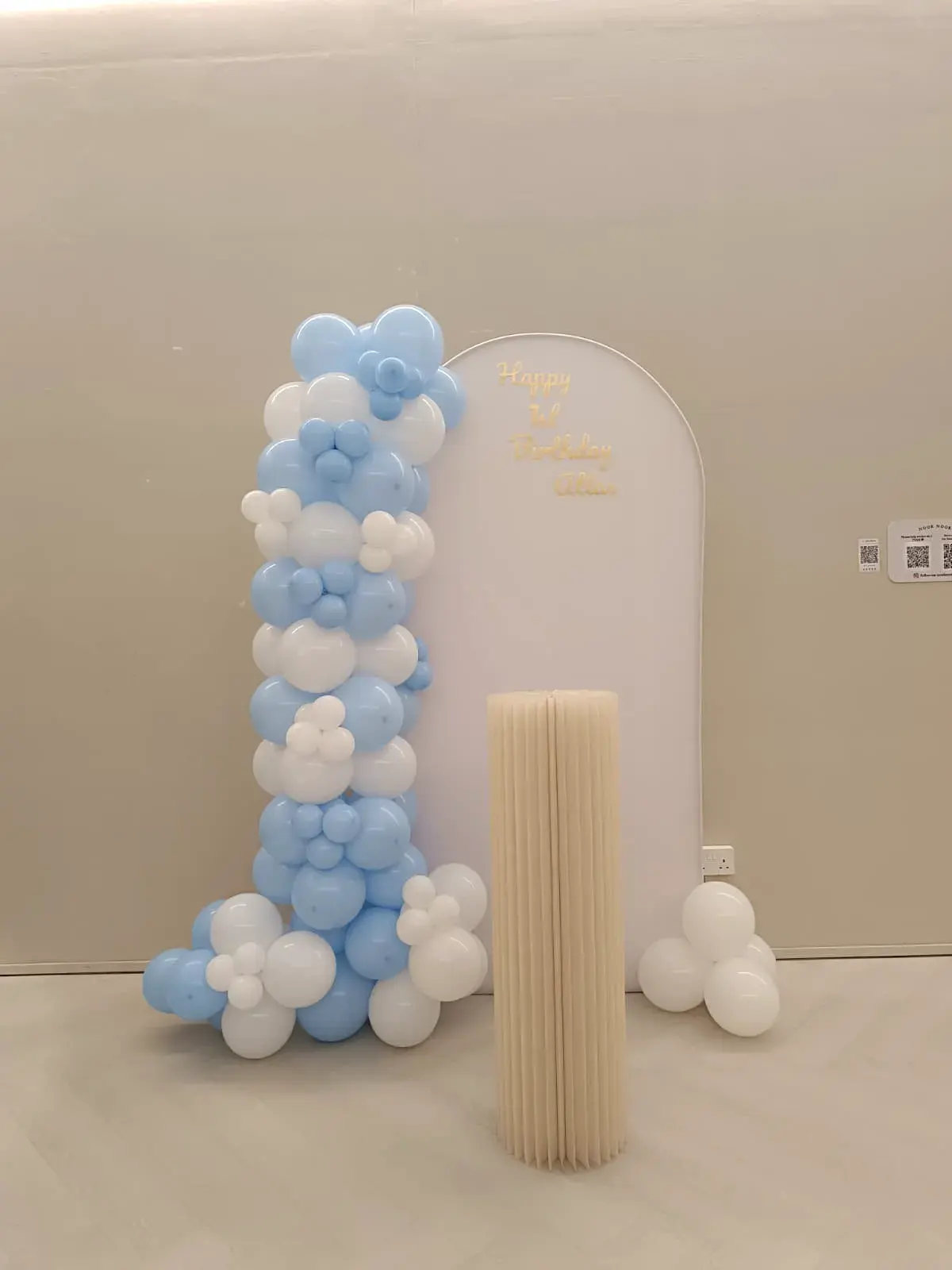 A blue balloon arch beside a fluted plinth