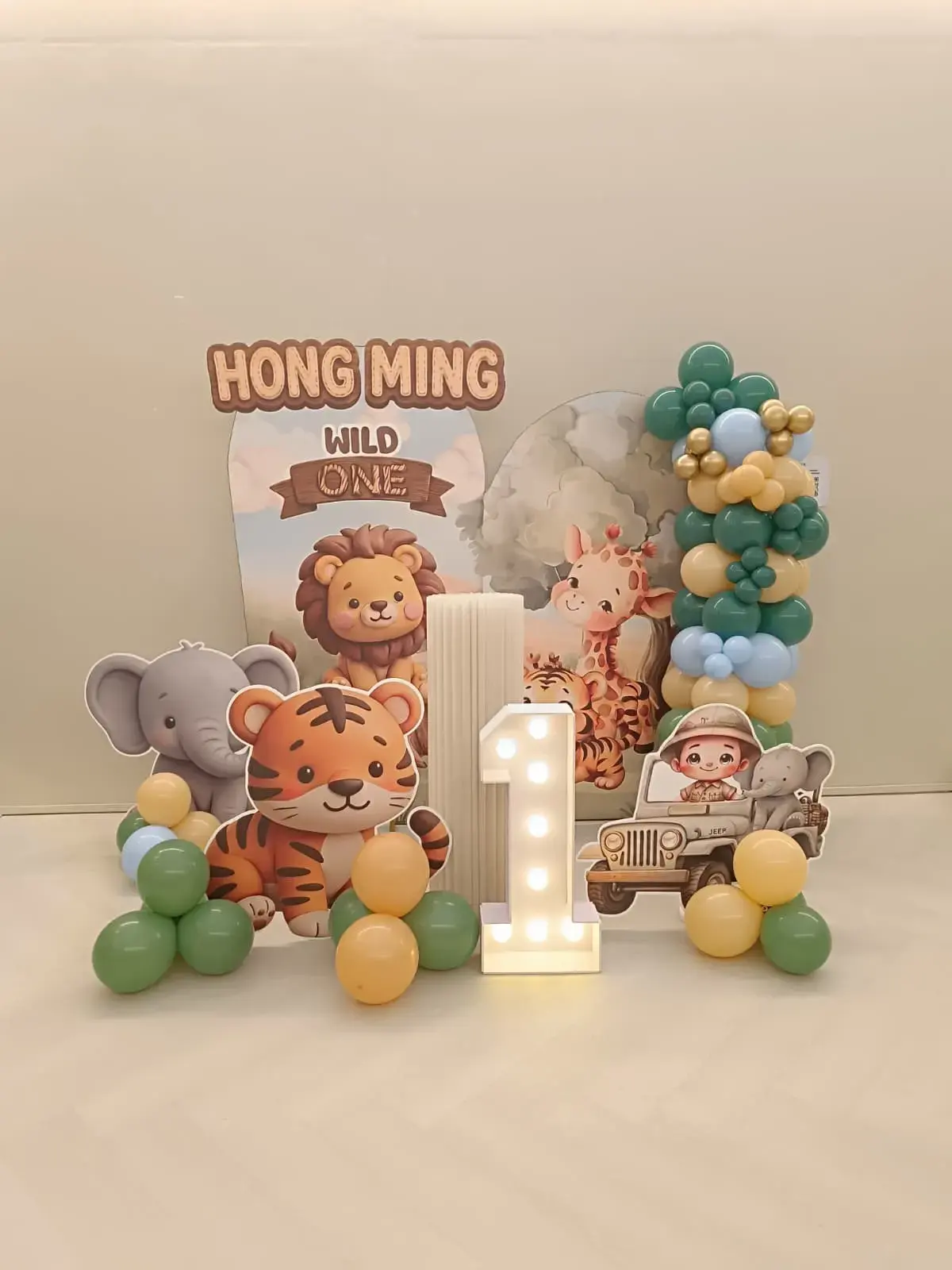 A safari themed first birthday backdrop with a light up number one