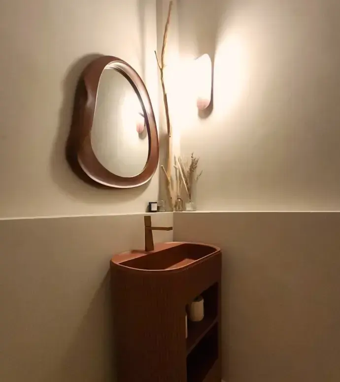 The restroom basin under a round mirror