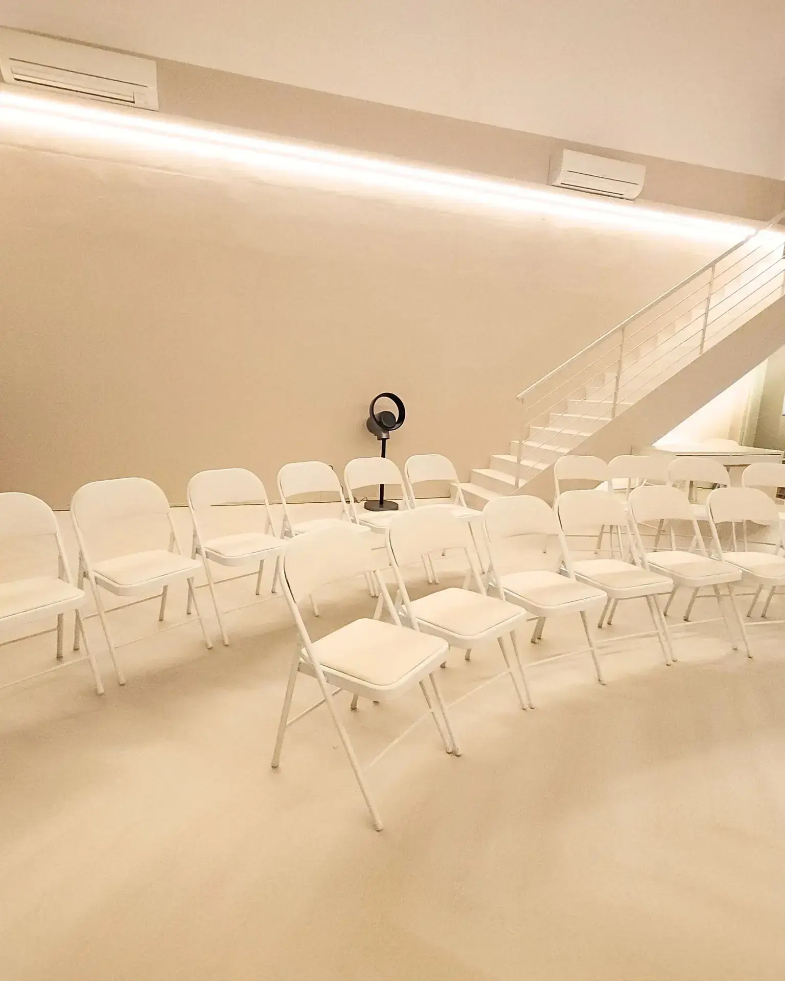 Rows of white chairs set out facing the front of the hall